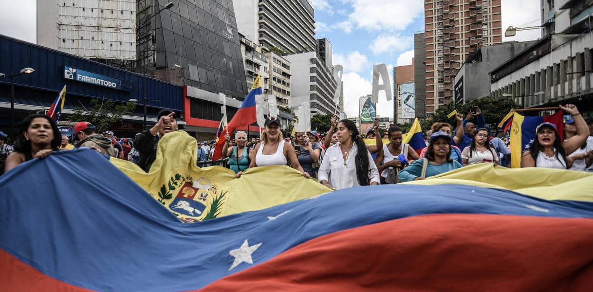 Protesters seen holding a huge Venezuela flag during a